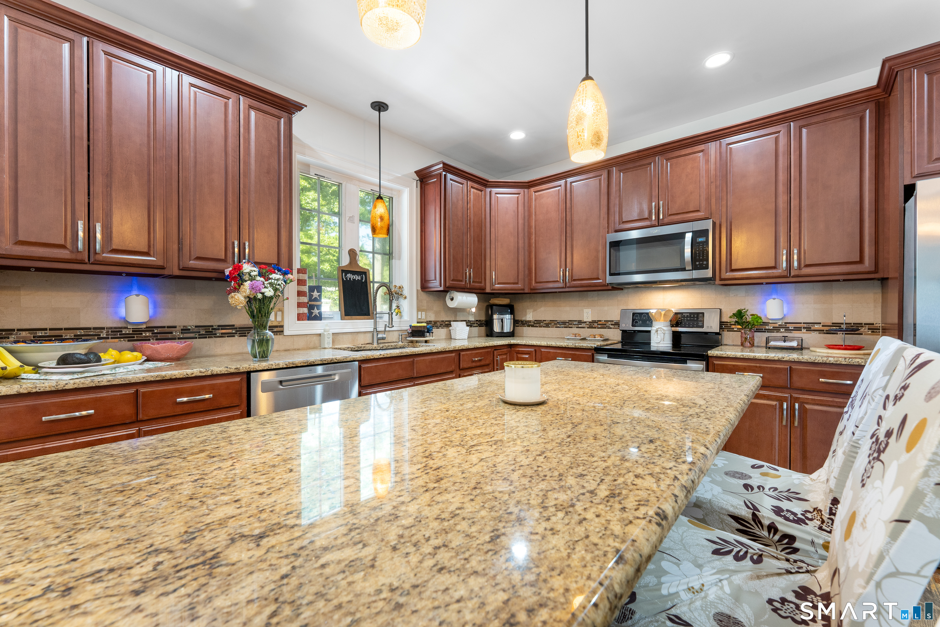 261 Spring Road North Haven, CT 06473 - Photo 20 of 39 a kitchen with kitchen island granite countertop wooden cabinets a stove top oven a granite counter top and a view of living room