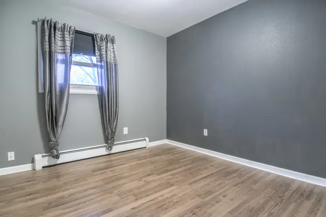 an empty room with wooden floor and a window