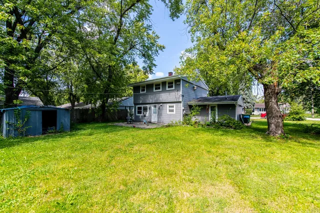 a view of a house with a big yard plants and large trees
