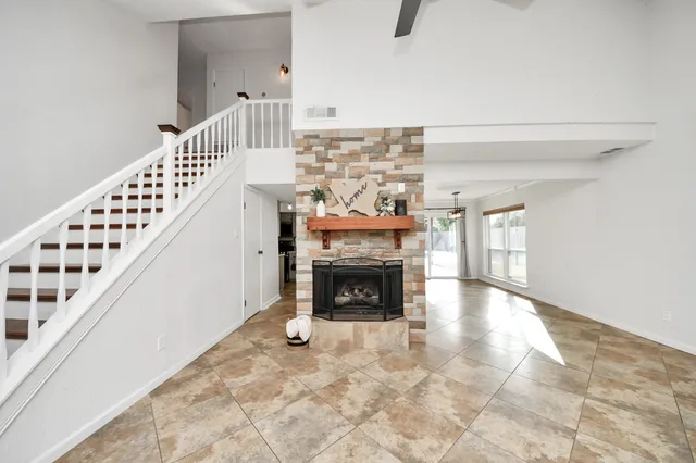 a view of an empty room with wooden floor fireplace and a window