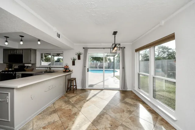 a large kitchen with kitchen island a large window cabinets and stainless steel appliances