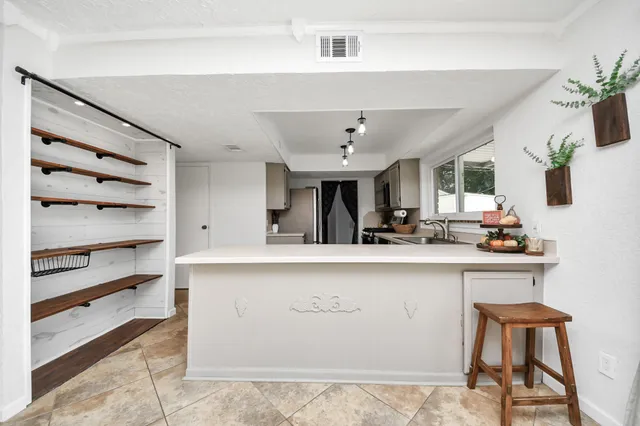 a view of cabinets a sink and chairs in a room