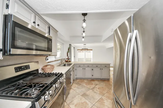 a kitchen with stainless steel appliances a stove a sink and a refrigerator