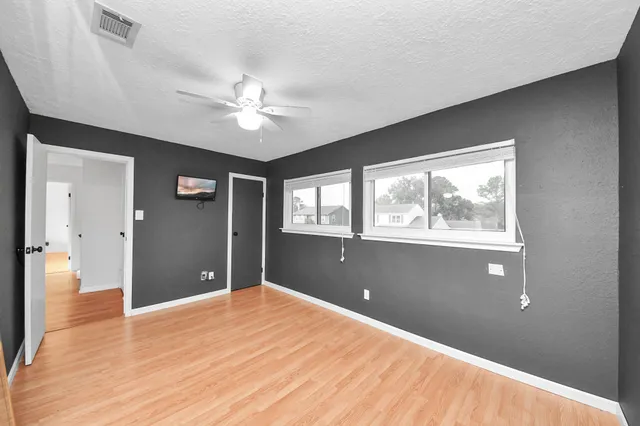 a view of an empty room with window and wooden floor