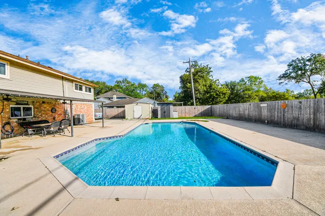 a swimming pool with outdoor seating and wooden fence