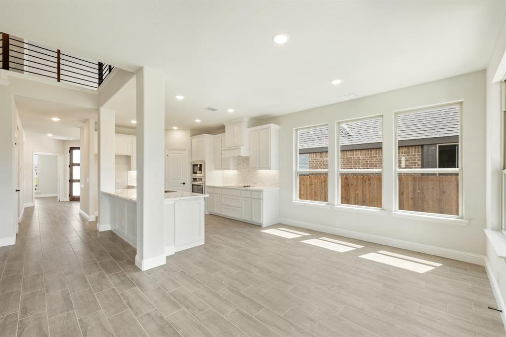 717 Seahawk Street Joshua, TX 76058 - Photo 13 of 40 a view of an empty room with wooden floor and a kitchen
