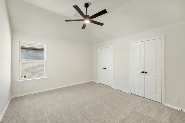 an empty room with ceiling fan and windows