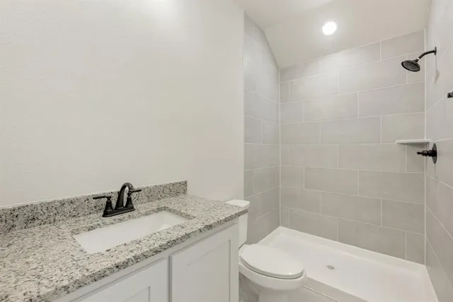 a bathroom with a granite countertop sink a toilet and shower