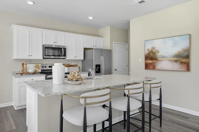 a kitchen with stainless steel appliances granite countertop a table chairs microwave and sink