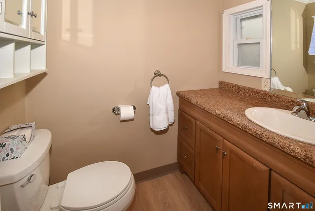 a bathroom with a granite countertop toilet sink and mirror