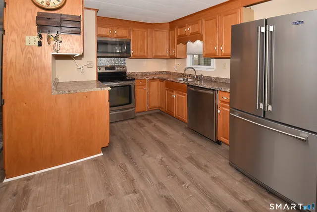 a kitchen with stainless steel appliances granite countertop a refrigerator a stove top oven a sink and dishwasher