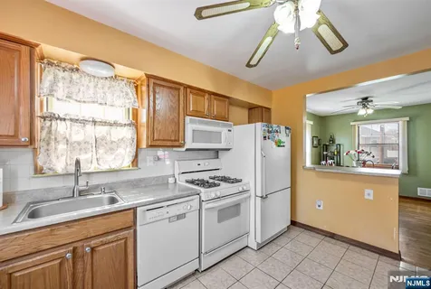 a kitchen with a refrigerator a sink and dishwasher with white cabinets