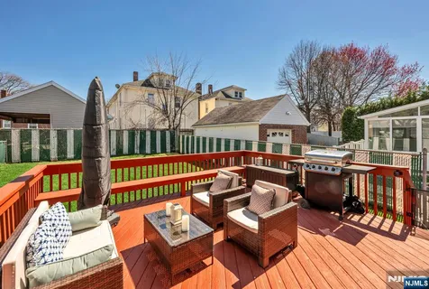 a view of a patio with couches table and chairs with wooden floor and fence