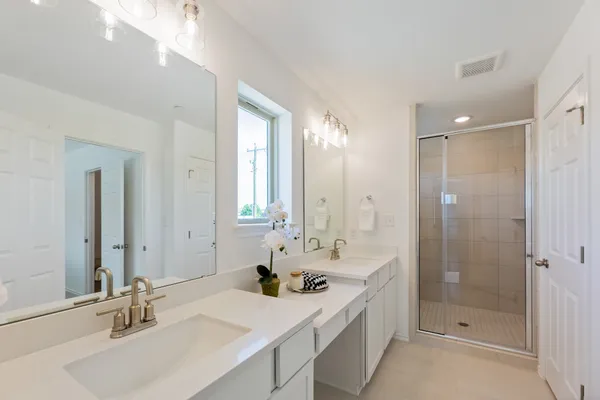 a bathroom with a double vanity sink mirror and shower