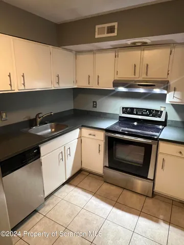 a kitchen with granite countertop a stove a sink and cabinets