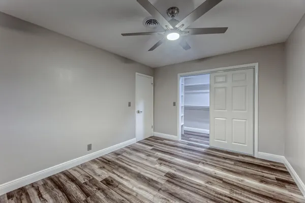 a view of a room with wooden floor and ceiling fan