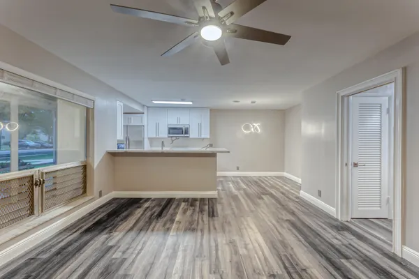 a view of kitchen and empty room with wooden floor