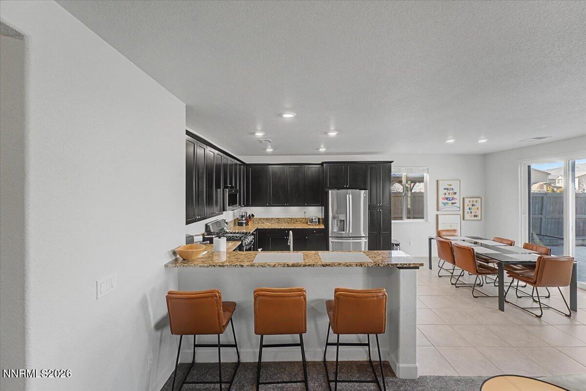 6997 Spencer Ridge Court Sparks, NV 89436 - Photo 10 of 38 a kitchen with stainless steel appliances kitchen island granite countertop a dining table chairs and a refrigerator