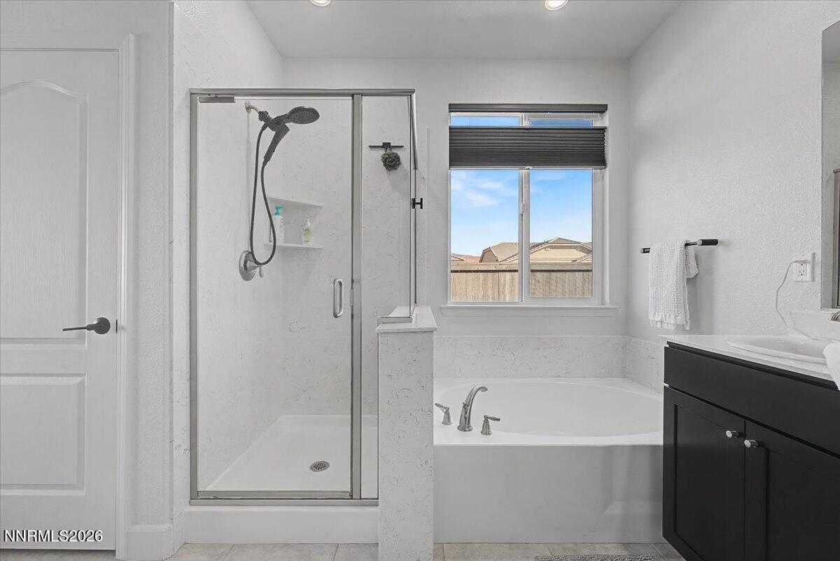 6997 Spencer Ridge Court Sparks, NV 89436 - Photo 17 of 38 a bathroom with a bathtub a mirror a vanity and a shower