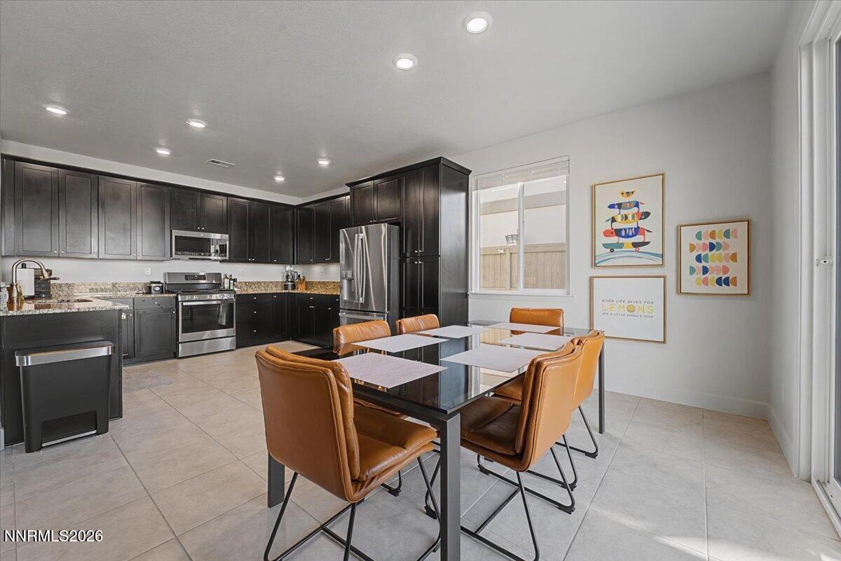 6997 Spencer Ridge Court Sparks, NV 89436 - Photo 2 of 38 a kitchen with stainless steel appliances kitchen island granite countertop a refrigerator a stove a sink a dining table and chairs