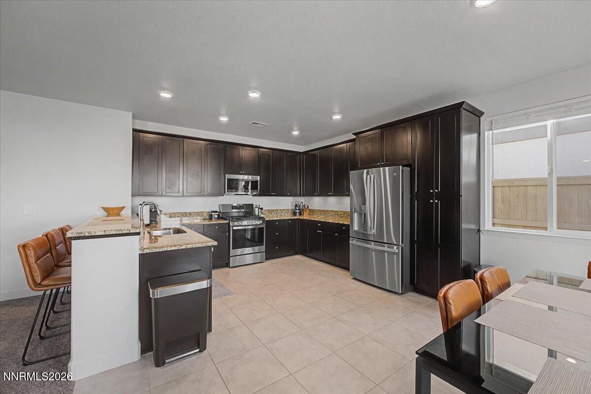 6997 Spencer Ridge Court Sparks, NV 89436 - Photo 4 of 38 a kitchen with stainless steel appliances kitchen island granite countertop a refrigerator and a stove top oven