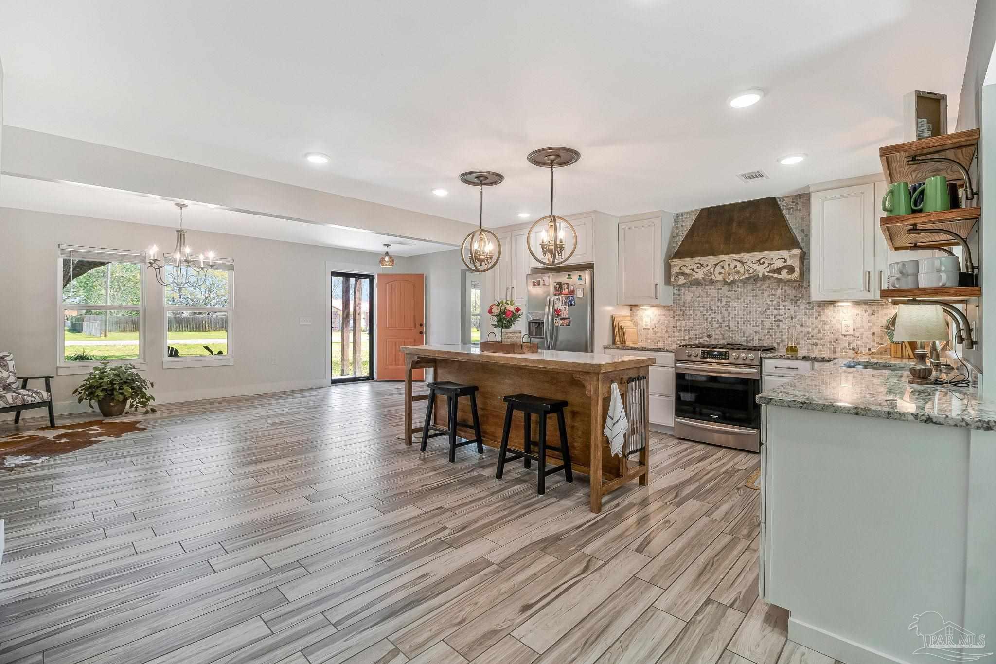 7175 Wallace Drive Pace, FL 32571 - Photo 24 of 71 a kitchen with stainless steel appliances kitchen island granite countertop a table and chairs in it