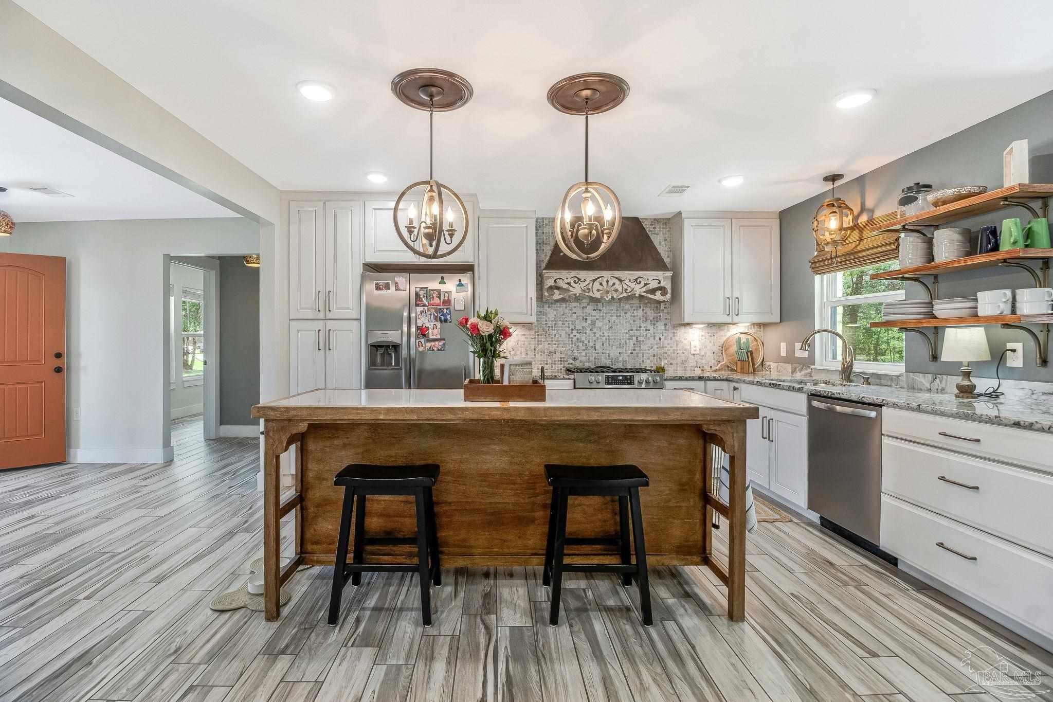 7175 Wallace Drive Pace, FL 32571 - Photo 26 of 71 a kitchen with stainless steel appliances a dining table chairs and wooden floor