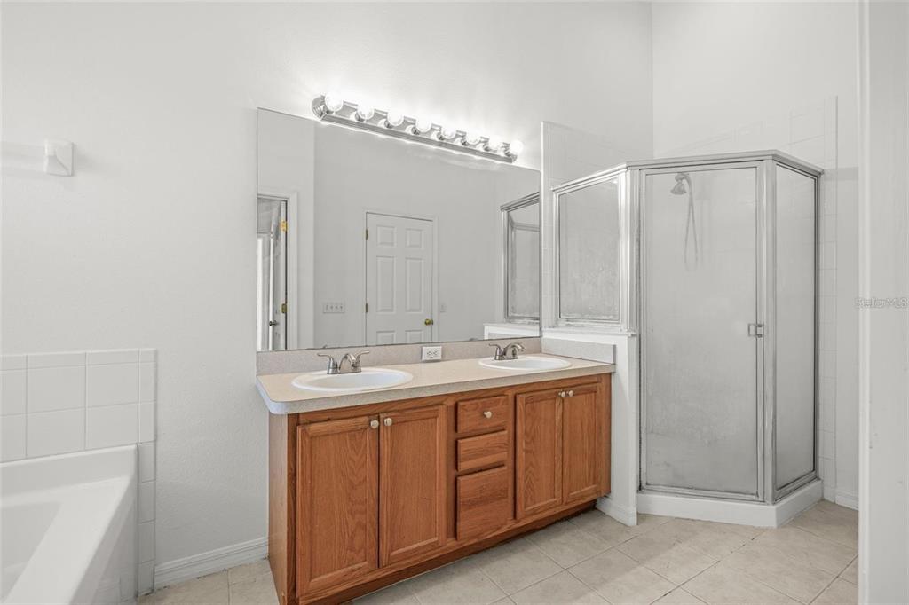 8010 Thoroughbred Loop Largo, FL 33773 - Photo 21 of 29 a bathroom with a double vanity sink a mirror and a bathtub
