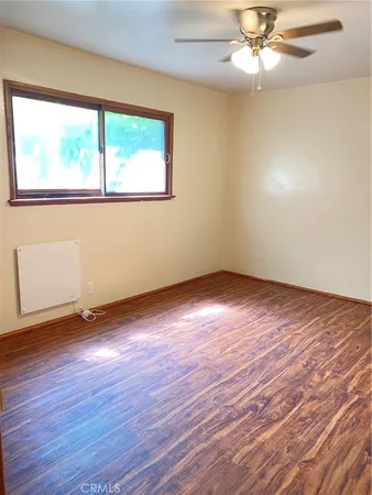 a view of an empty room with wooden floor and a window