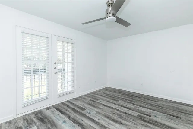 an empty room with wooden floor and windows