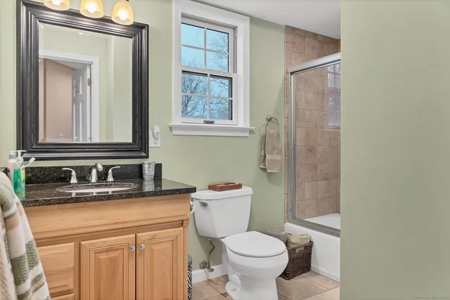 a bathroom with a granite countertop sink toilet and mirror