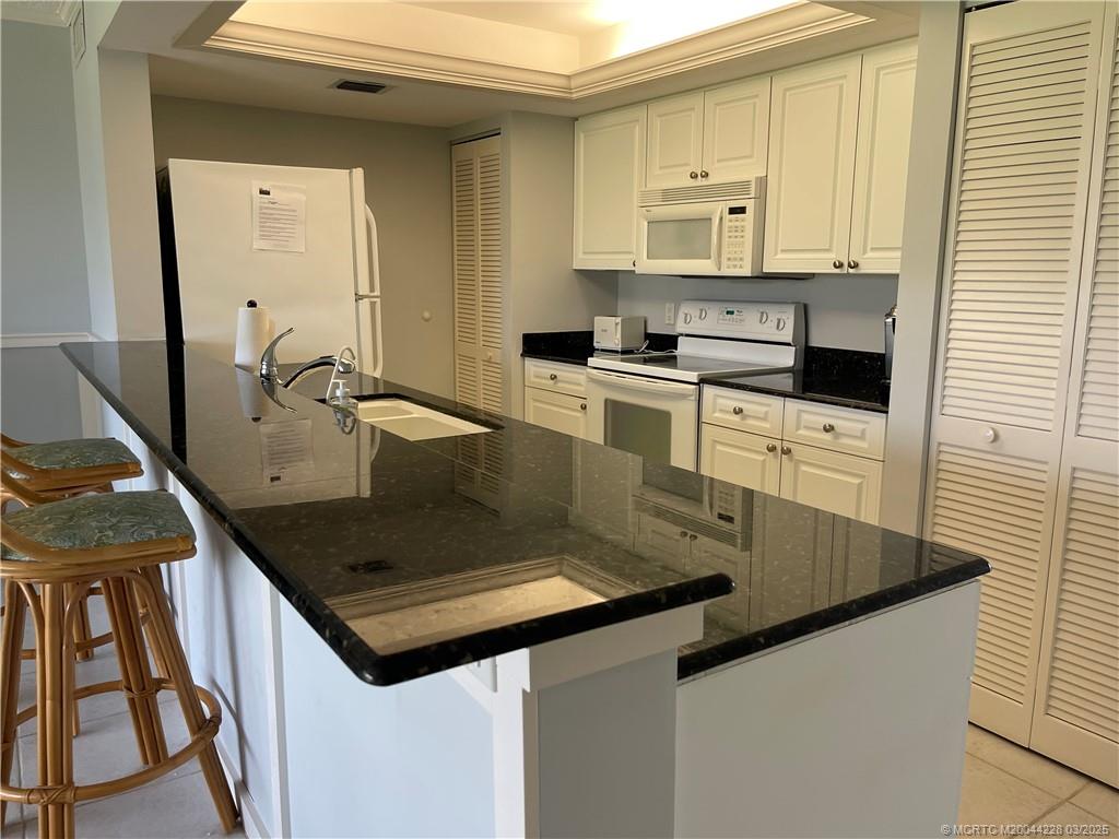 5565 Northeast Gulfstream Way Stuart, FL 34996 - Photo 11 of 21 a kitchen with kitchen island a sink stove and cabinets