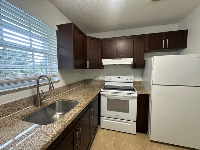 a kitchen with granite countertop a sink stove and refrigerator