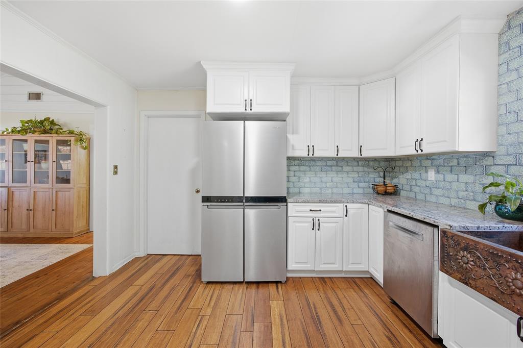 10550 Northeast 222nd Place Road Fort McCoy, FL 32134 - Photo 15 of 48 a kitchen with wooden floors white cabinets and stainless steel appliances