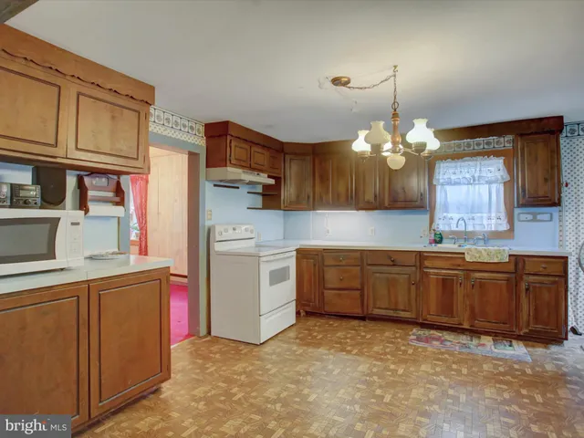 an empty room with chandelier fan and windows