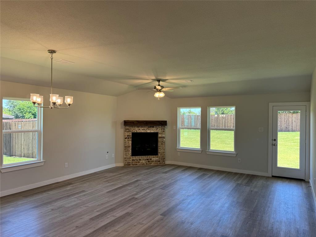 612 Finlee Way Tioga, TX 76271 - Photo 11 of 23 an empty room with windows fireplace and wooden floor