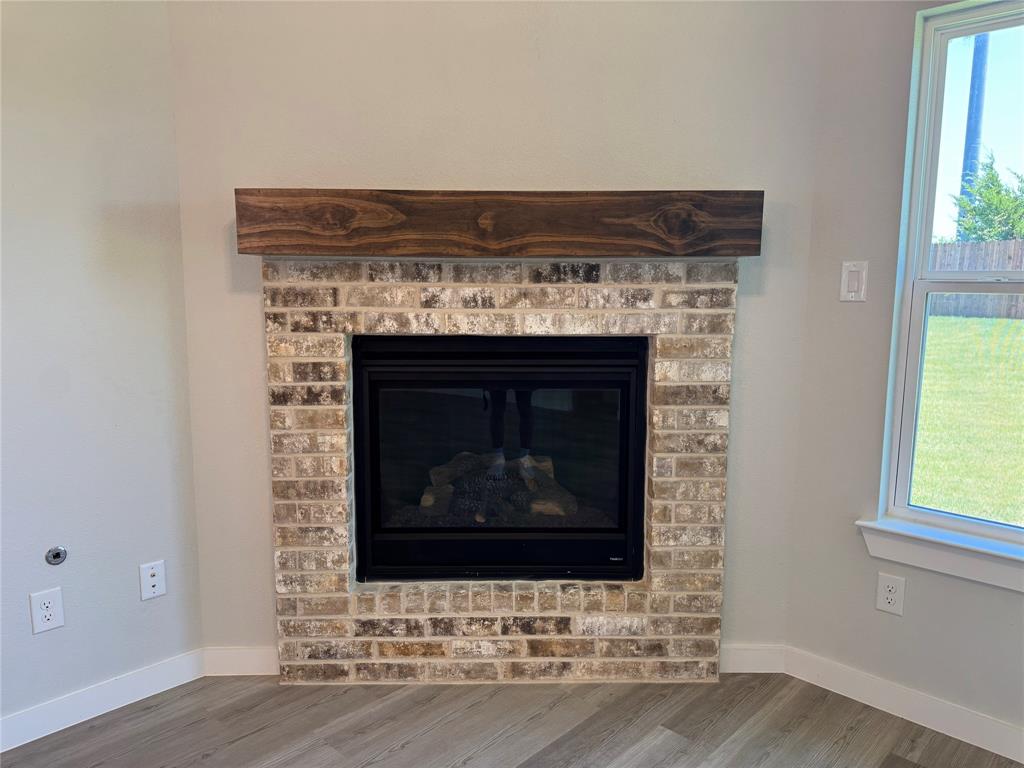 612 Finlee Way Tioga, TX 76271 - Photo 12 of 23 a fireplace with a clock on wooden floor