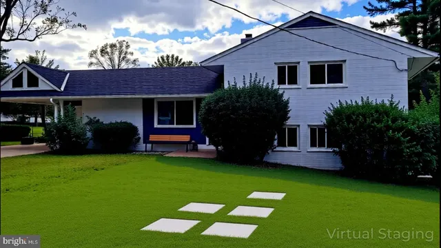 a view of a house with a yard plants and large tree