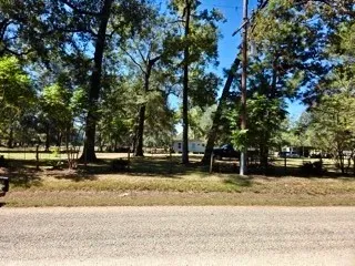 a view of a yard with a house and trees in the background