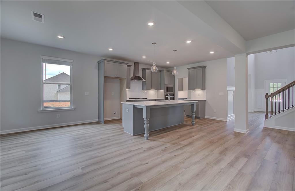 116 Haverling Pass Hampton, GA 30228 - Photo 12 of 38 a open kitchen with kitchen island a sink dishwasher a refrigerator and white cabinets with wooden floor
