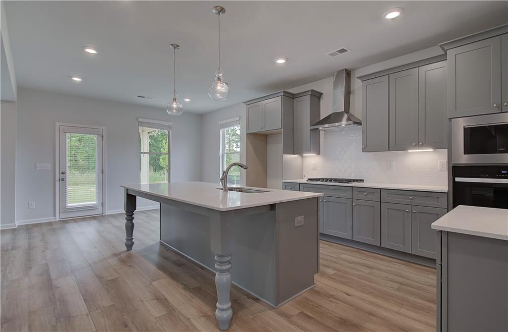 116 Haverling Pass Hampton, GA 30228 - Photo 10 of 38 a kitchen with kitchen island granite countertop a sink cabinets and wooden floor