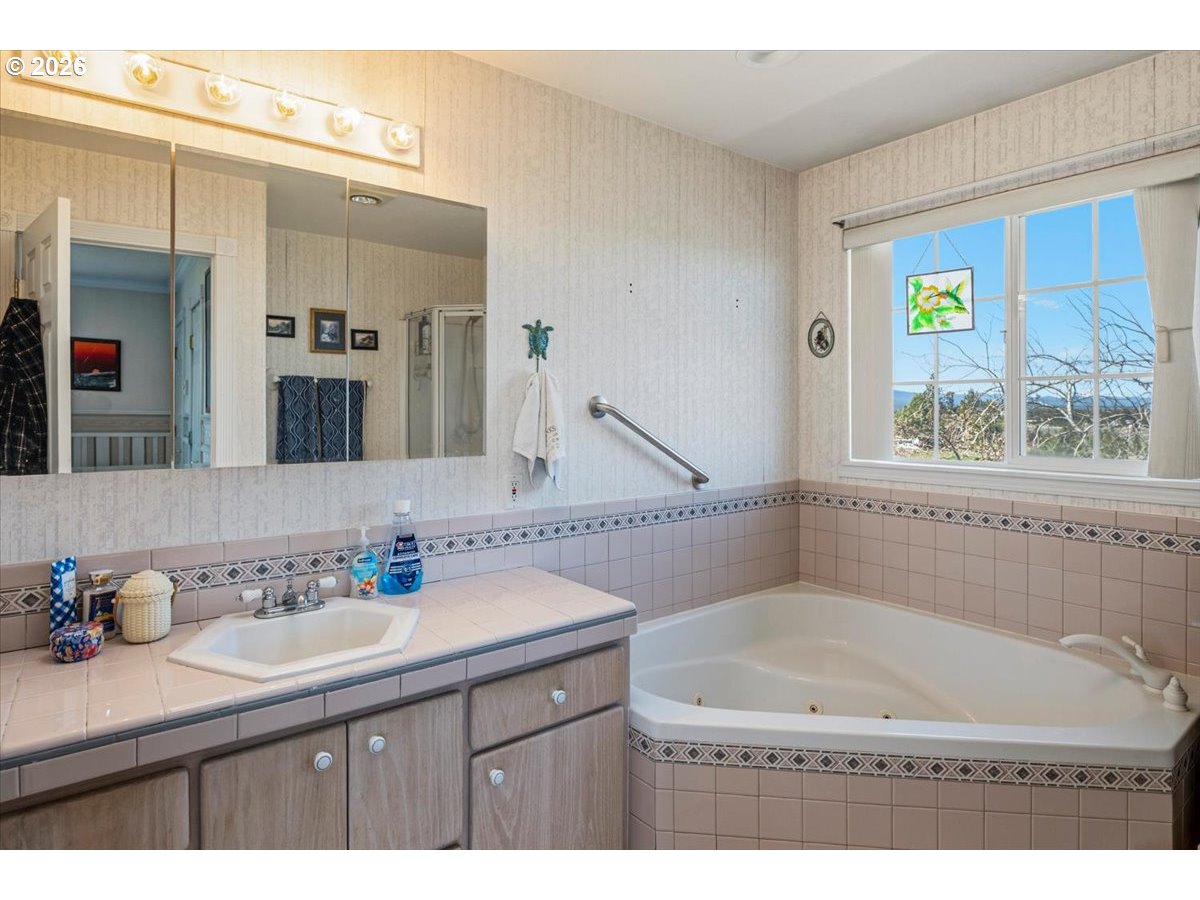 8818 Southwest Panorama Road Terrebonne, OR 97760 - Photo 28 of 46 a bathroom with a granite countertop sink a mirror a bathtub and next to a window