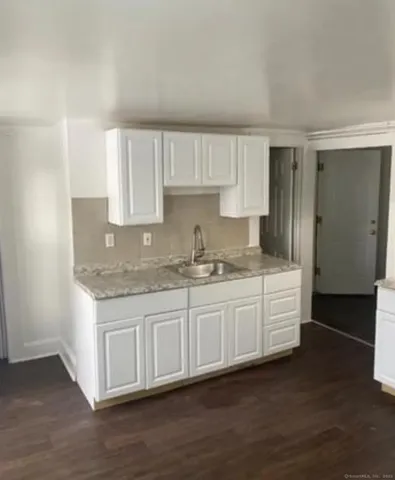 a kitchen with granite countertop white cabinets and a sink
