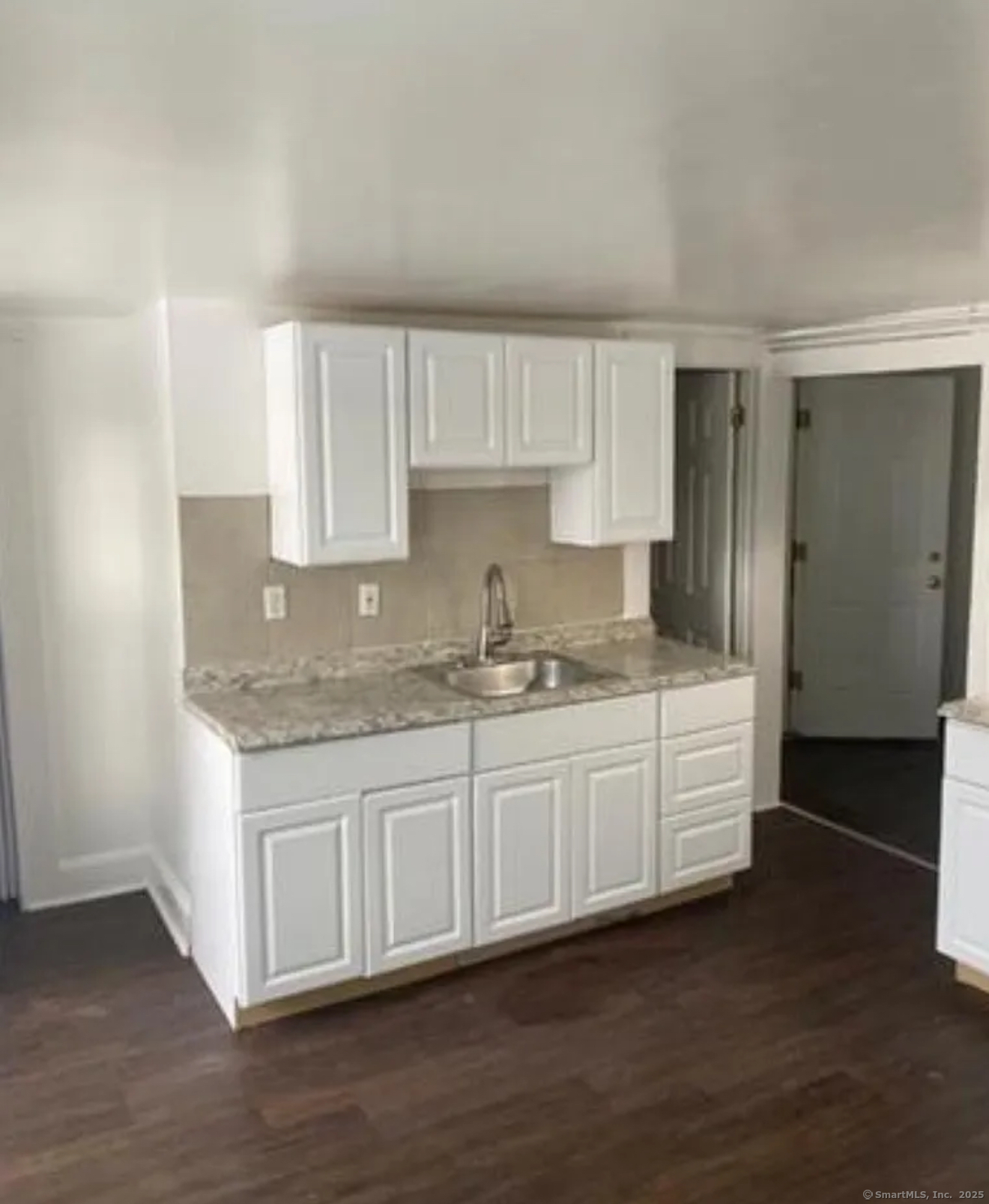 a kitchen with granite countertop white cabinets and a sink