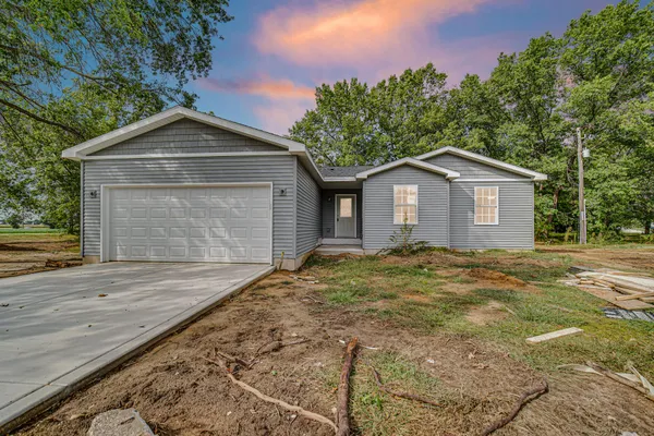 a view of a house with a yard plants and large tree