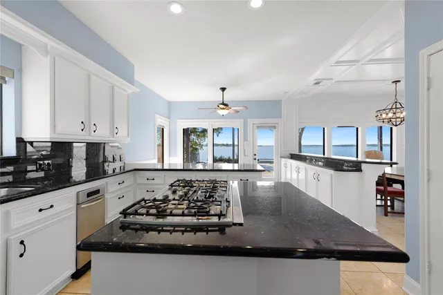 a large kitchen with stainless steel appliances granite countertop a stove and white cabinets