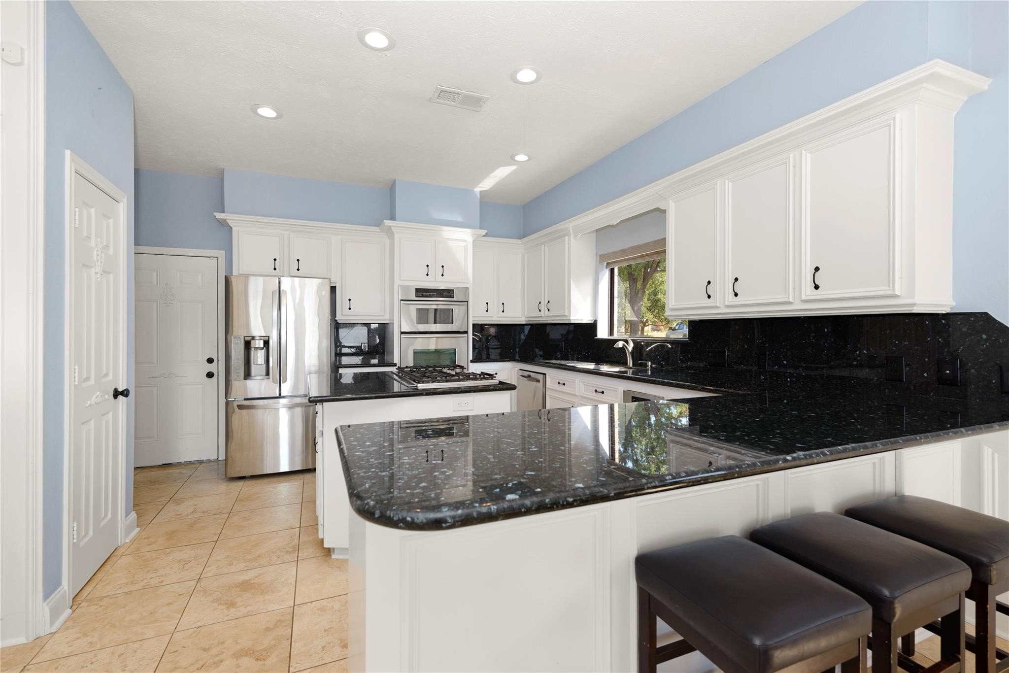 12098 Sagittarius East Willis, TX 77318 - Photo 12 of 37 a kitchen with stainless steel appliances granite countertop a stove a refrigerator a sink a dining table and chairs