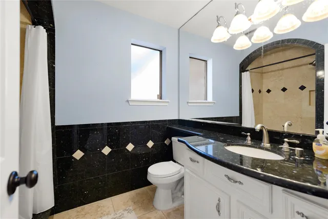 a bathroom with a granite countertop sink toilet and mirror