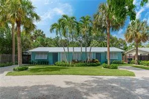a view of a house with a yard and palm trees