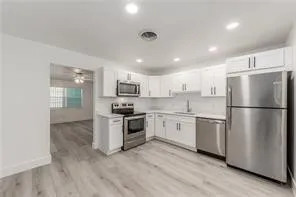 a kitchen with stainless steel appliances granite countertop a refrigerator a stove top oven a sink and dishwasher